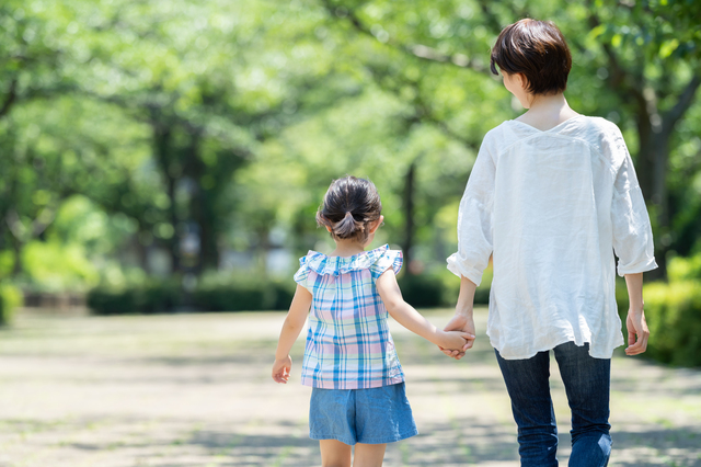 手をつないで歩く親子の後ろ姿