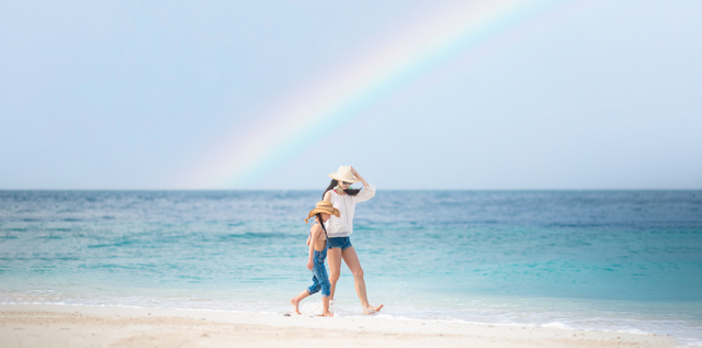 虹の出たビーチで遊ぶ親子
