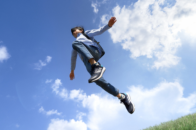 青空のもとでジャンプする男の子